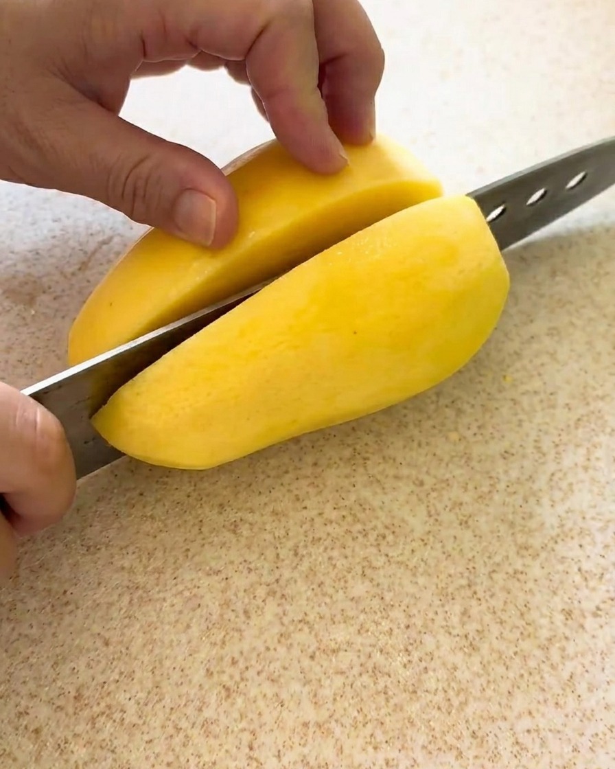 Potatoes being sliced into even cubes on a clean cutting board, ready for the stew.