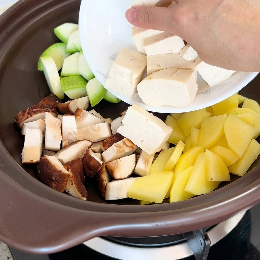 Tofu pieces and dried clams being placed into the pot along with the other ingredients.