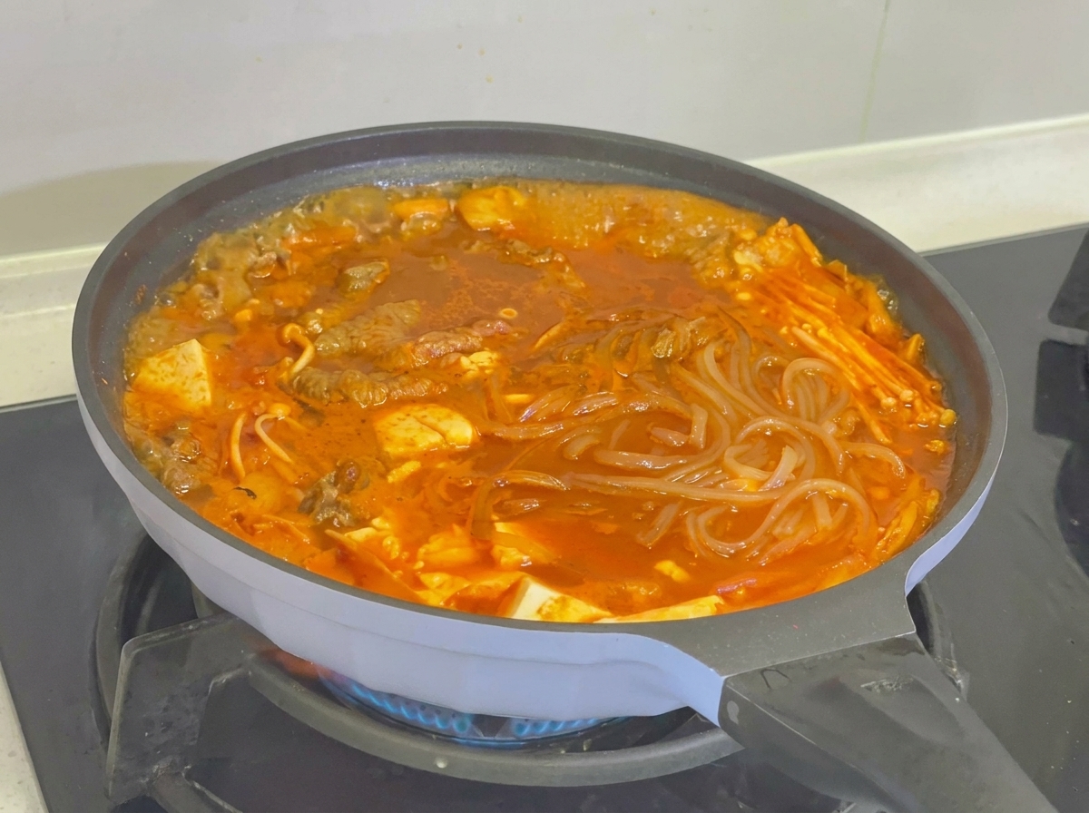 Close-up of the finished kimchi beef tofu soup topped with colorful chili pepper slices.
