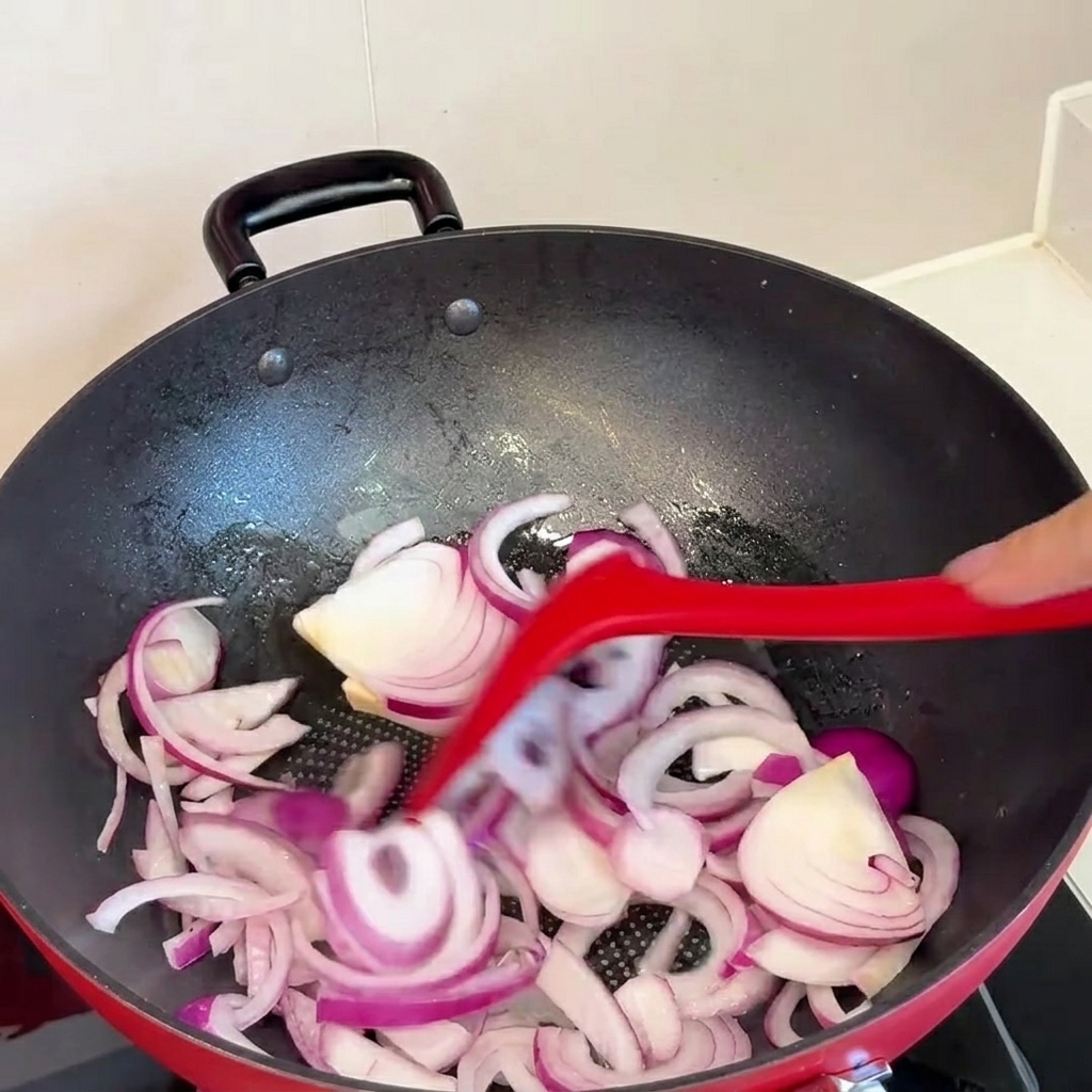 Kimchi being added to the pan with sautéed onions.
