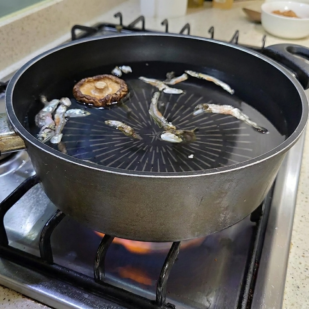 A dried shiitake mushroom floating in the pot of water with anchovies.
