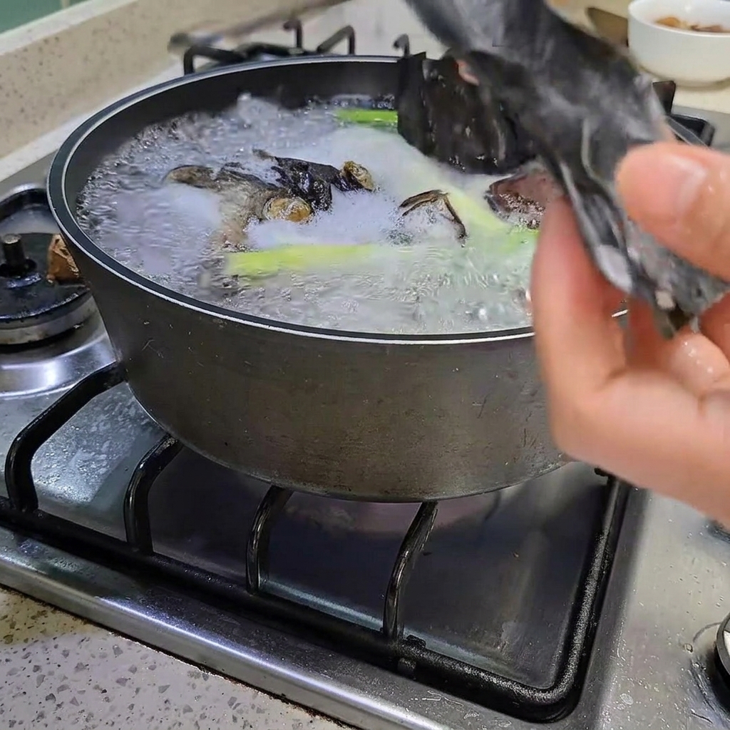 Tongs removing a piece of kelp from the boiling pot.