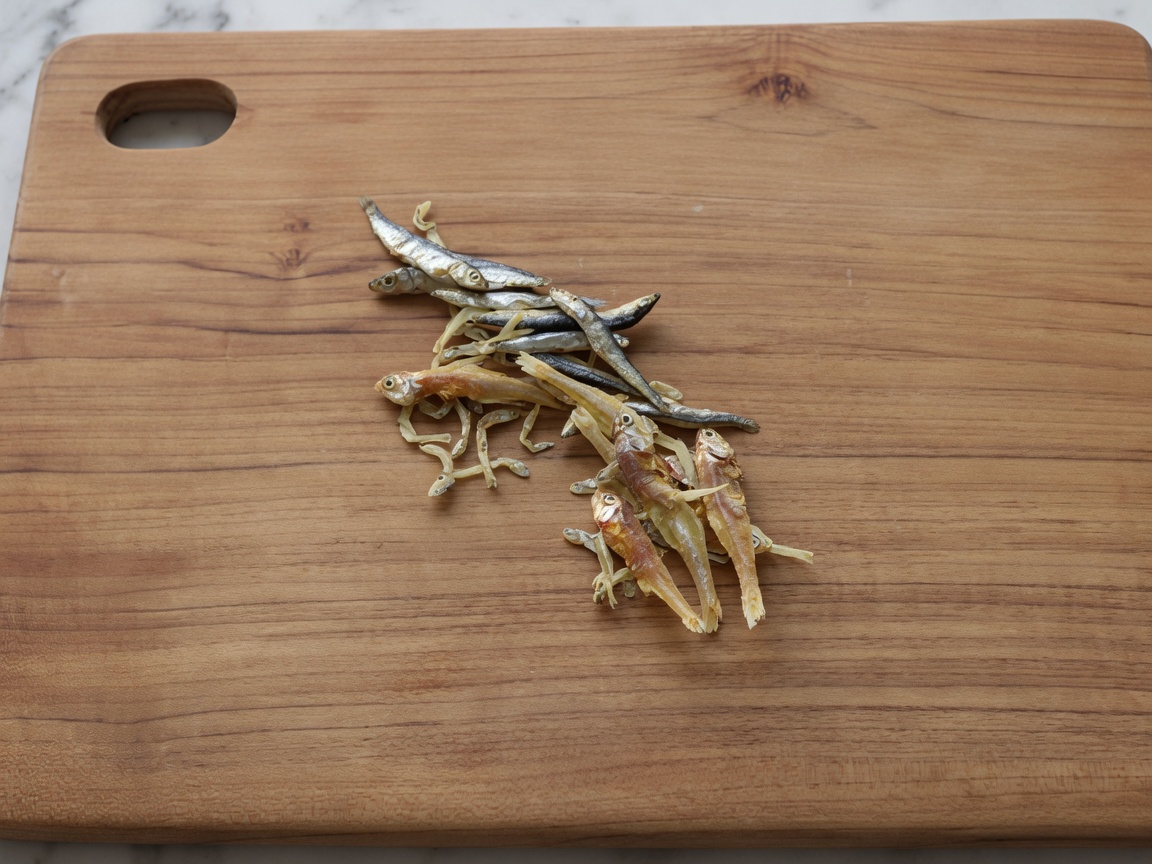 Dried anchovies on a wooden board after having their heads and innards removed.