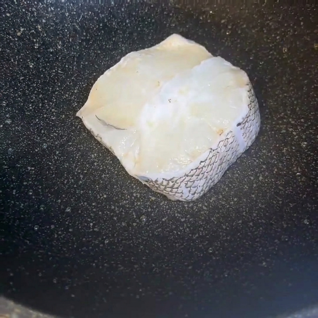 Freshly cleaned pieces of cod fillet arranged neatly inside a dark cooking pan.