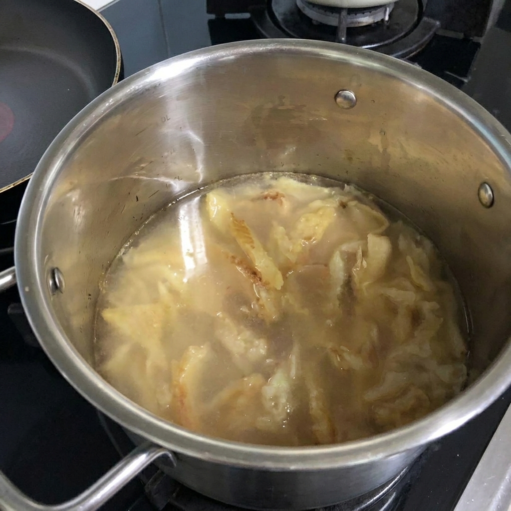 Water being poured from a bottle into the pot containing stir-fried pollack.