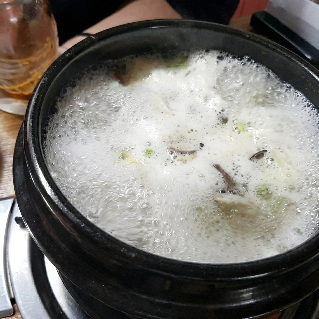 Mixing brown soybean paste into the broth inside the stone pot.