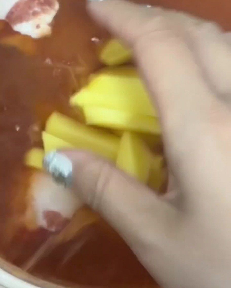 Fresh potato strips being dropped into the boiling red broth.