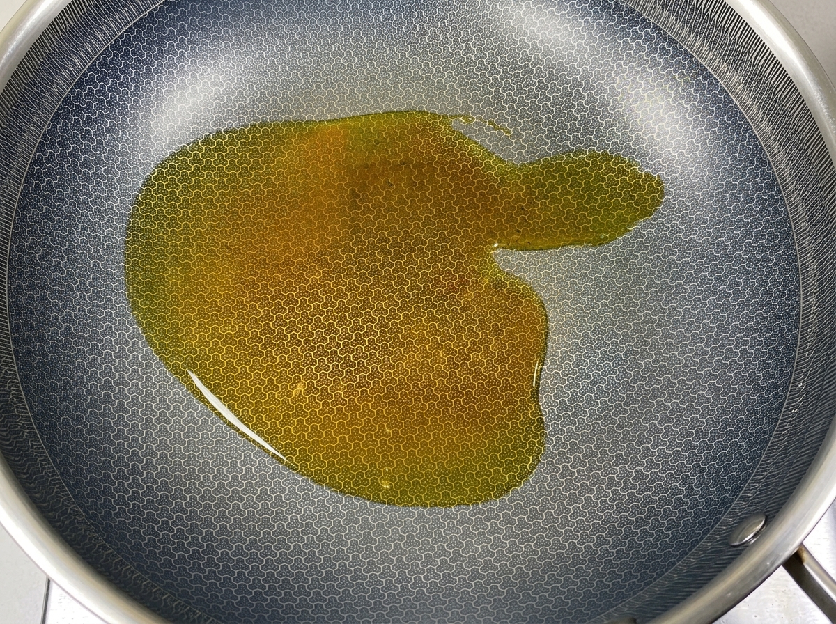 A chunk of white solid lard melting into hot cooking oil in a dark, textured wok.