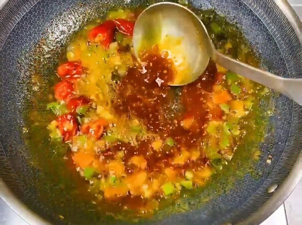 Clear water being poured into the seasoned wok base to form a flavorful broth.