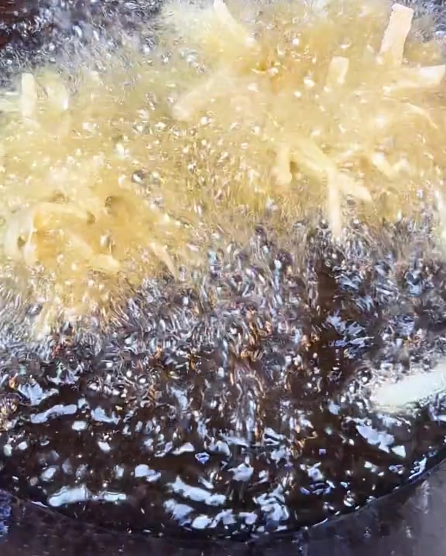 Crispy potato shreds frying in bubbling hot oil until golden brown.