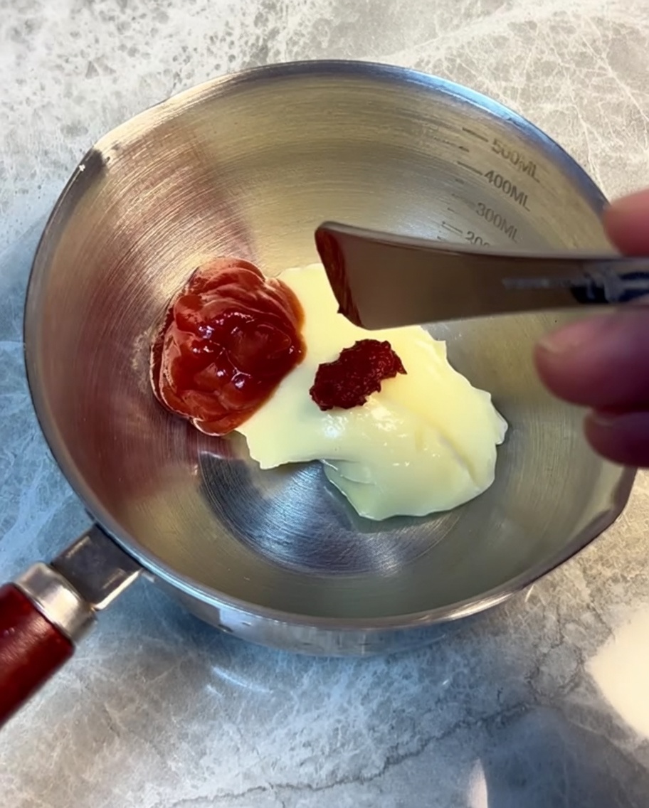 Ingredients for burger sauce being mixed in a stainless steel cup.