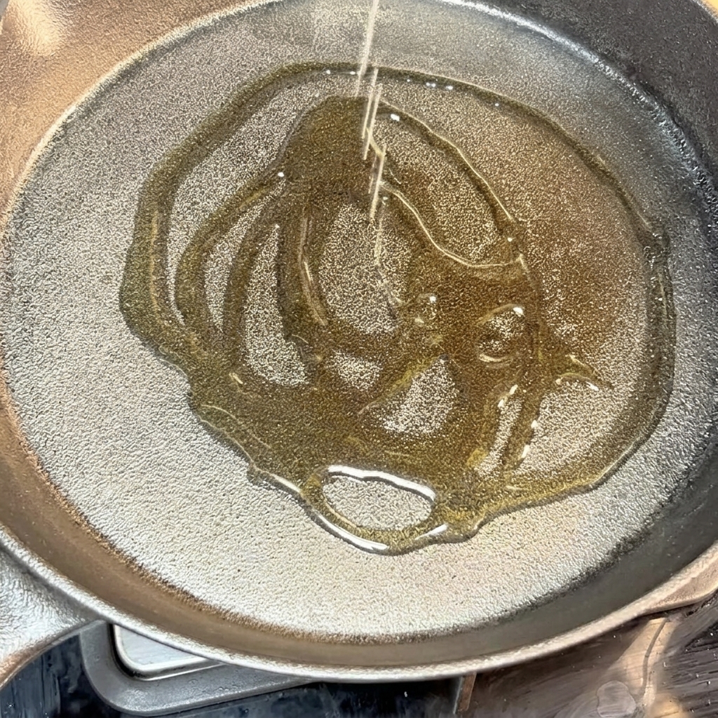 Seasoned beef patty sizzling in a hot cast-iron skillet with oil.