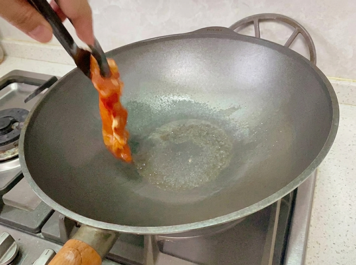 Marinated chicken cooking in a pan over medium-low heat.