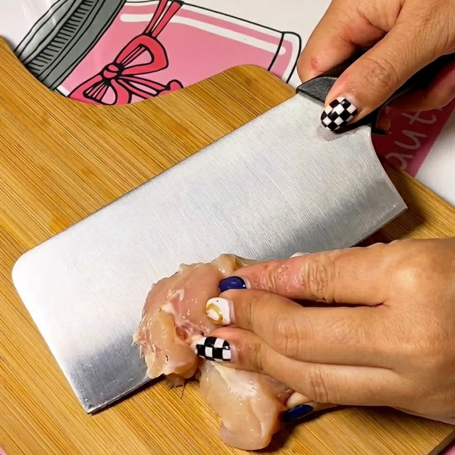 Thin slices of raw chicken breast neatly arranged on a clean wooden cutting board.