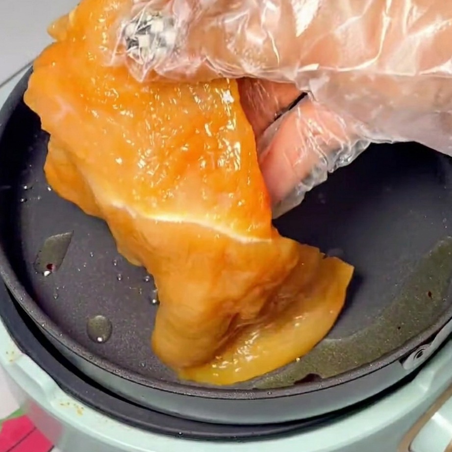 Marinated chicken slices browning beautifully in a hot, oiled frying pan.