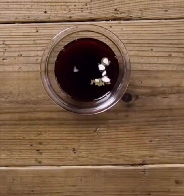 Dark teriyaki sauce mixture with visible white bits of starch and sugar in a small glass bowl on a wooden surface.