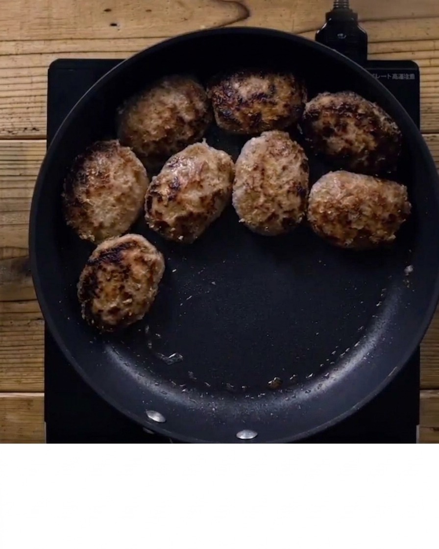 Teriyaki sauce being poured over browned hamburger steaks in a pan.