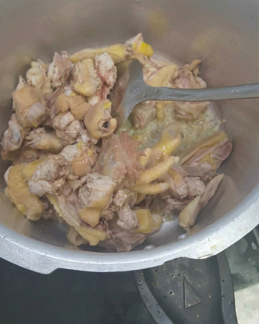 Slices of galangal being stirred into the chicken mixture.