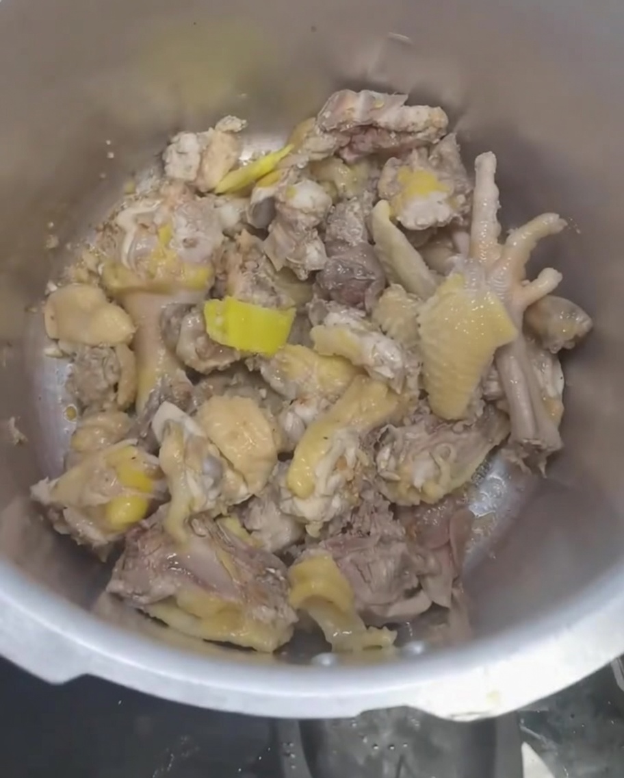 Water being poured into the pressure cooker over the chicken and aromatics.