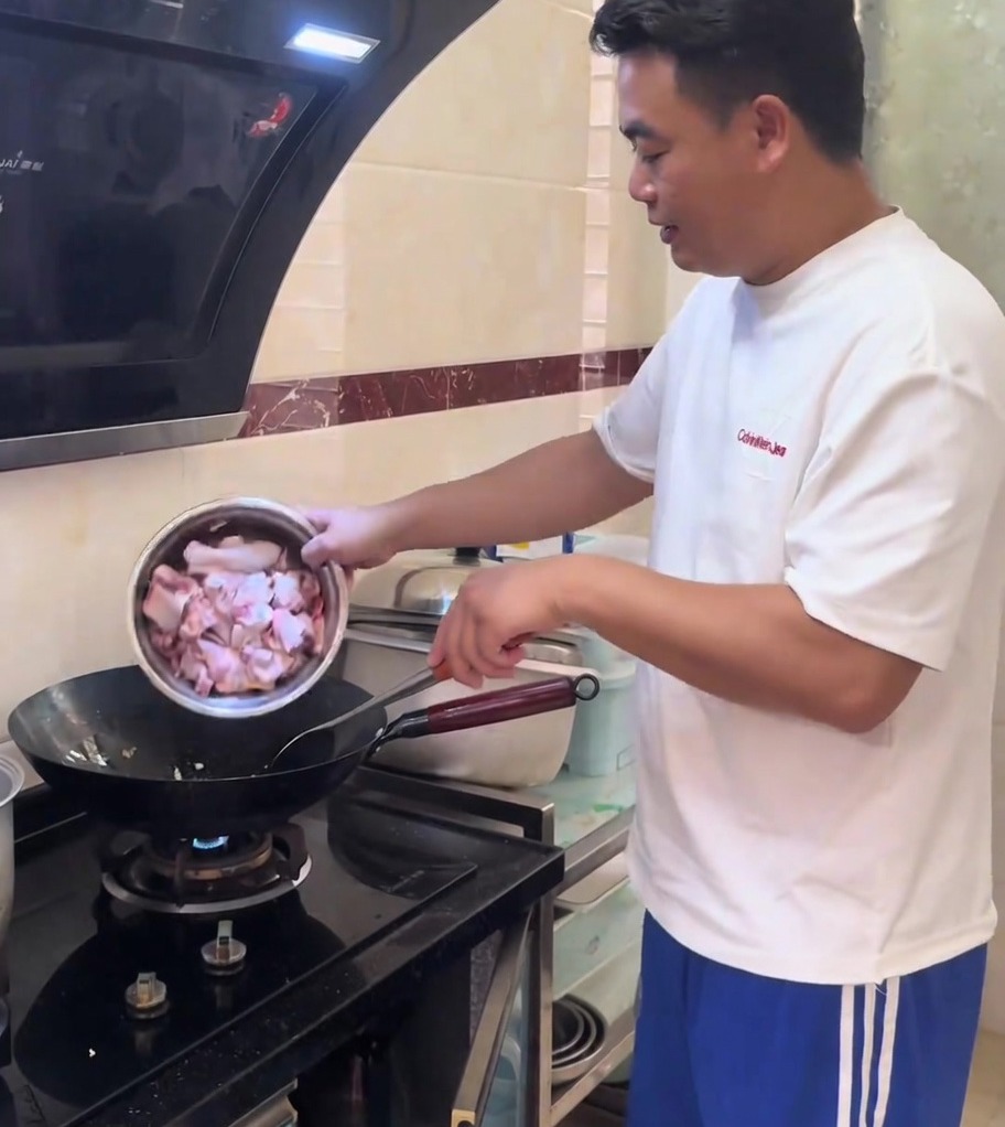 Chicken pieces being stir-fried with minced ginger in a hot, glistening wok.