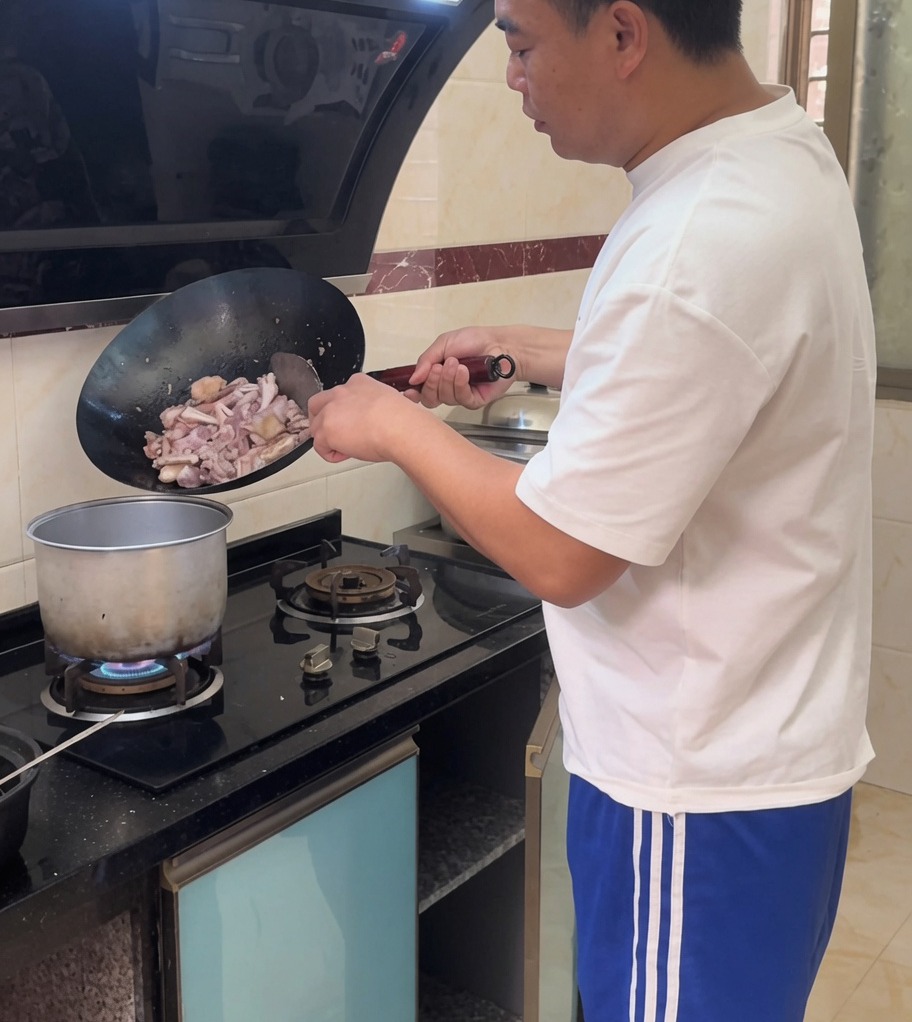 The stir-fried chicken mixture being poured into a large pot of simmering water.