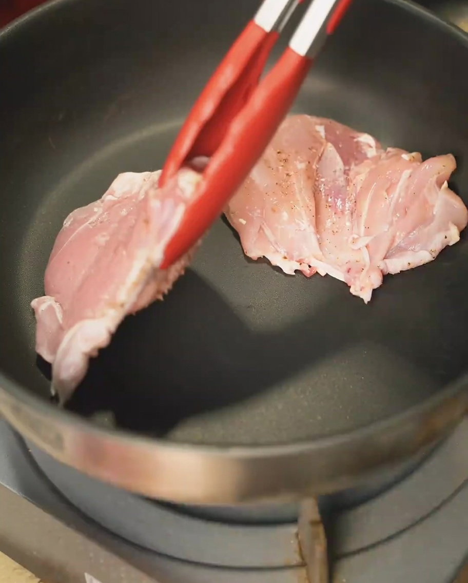 Chicken thighs searing in a pan, skin-side down, achieving a golden-brown crust.