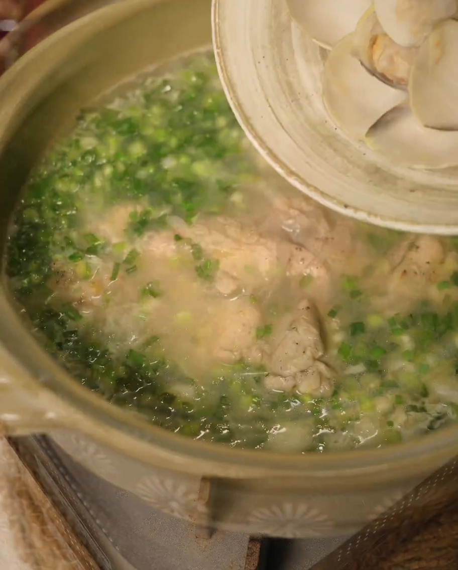 Onion strips and garlic cloves browning in rendered chicken fat in a pan.