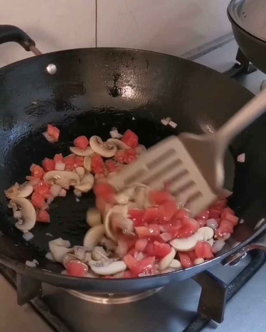 Chopped vegetables and mushrooms cooking in a hot wok with olive oil.