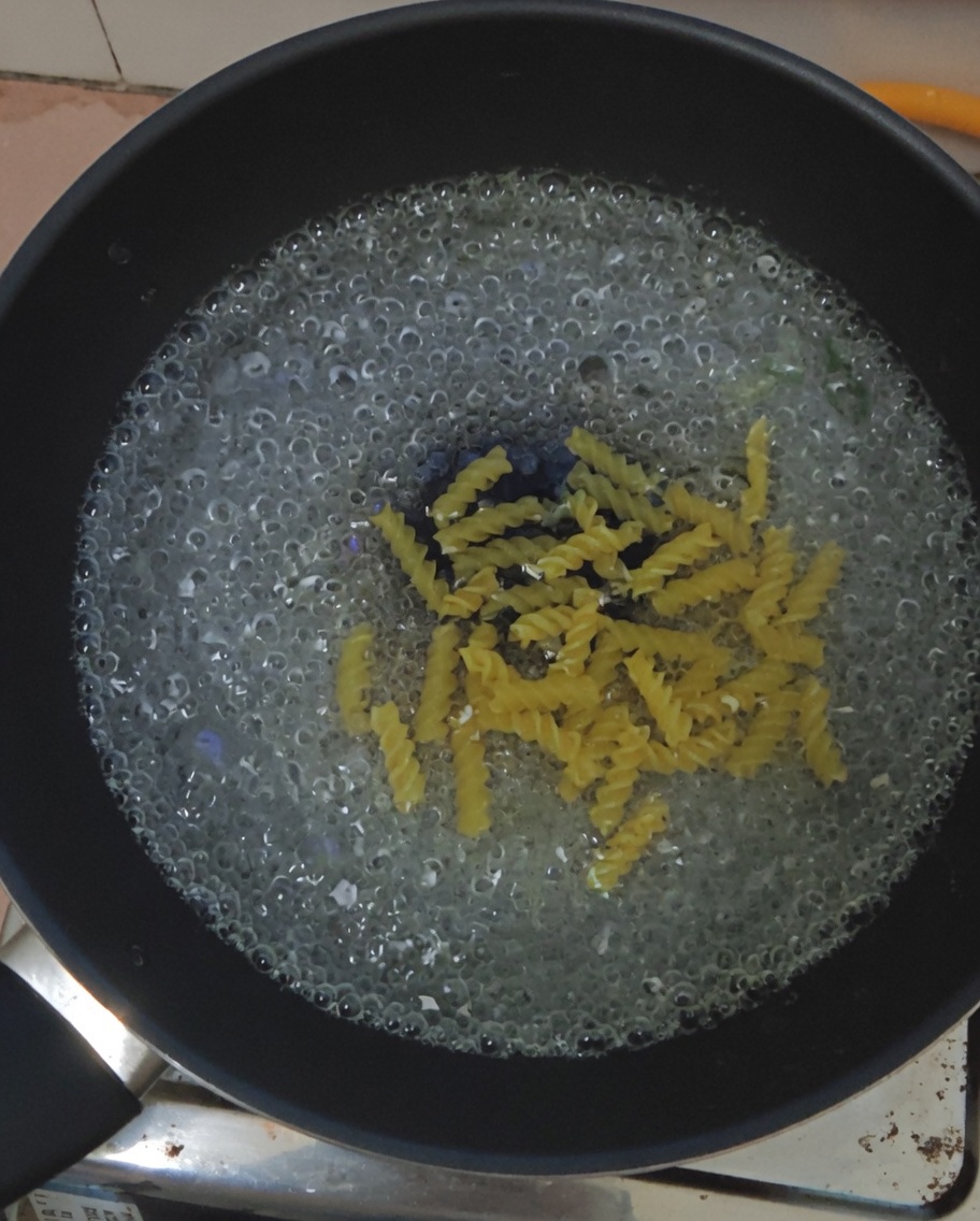 Fusilli pasta submerged in a pot of boiling water.