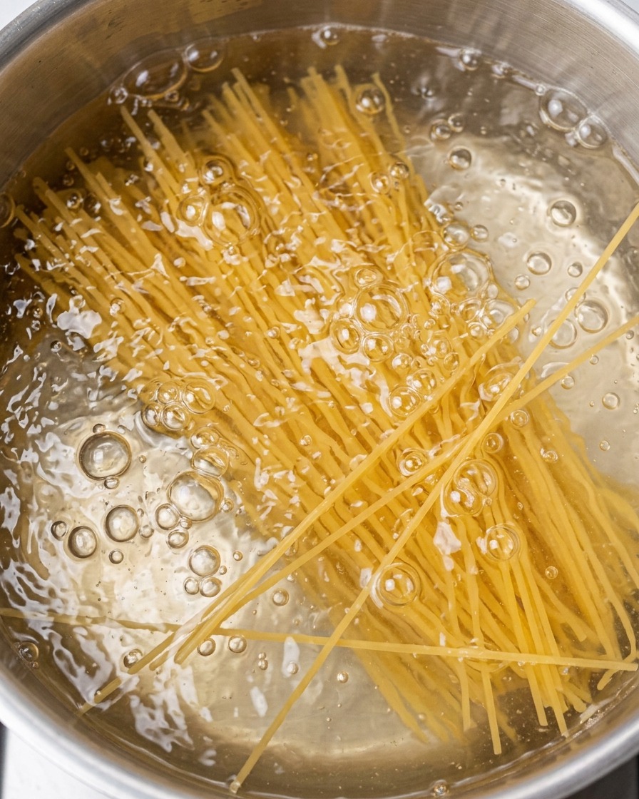 Spaghetti noodles cooking in a pot of boiling water.