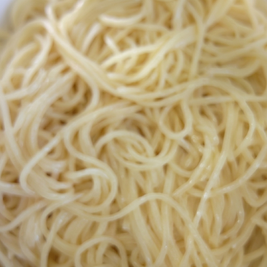 A bowl of cooked spaghetti being tossed with oil.