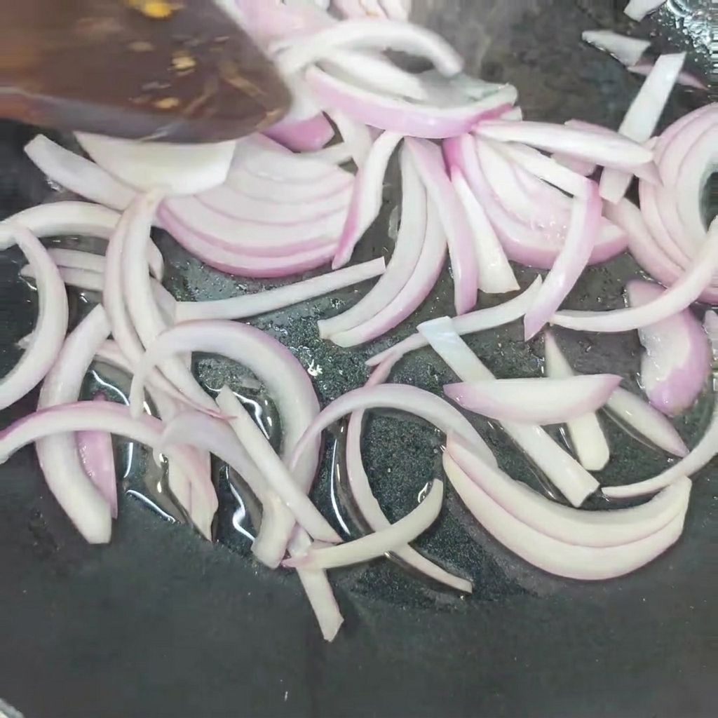 Onions frying in a pan until soft.