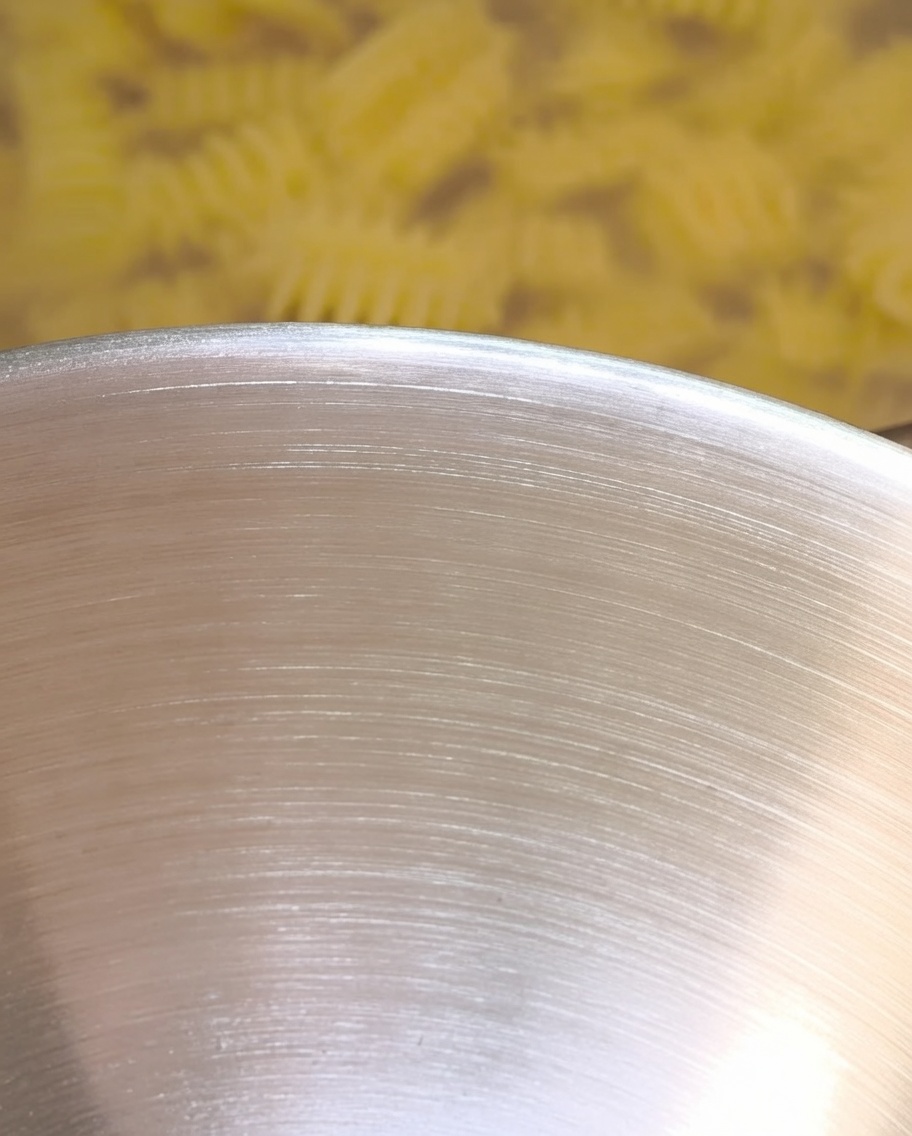 Hot pasta water being poured into the mixing bowl, interacting with the butter and seasonings.