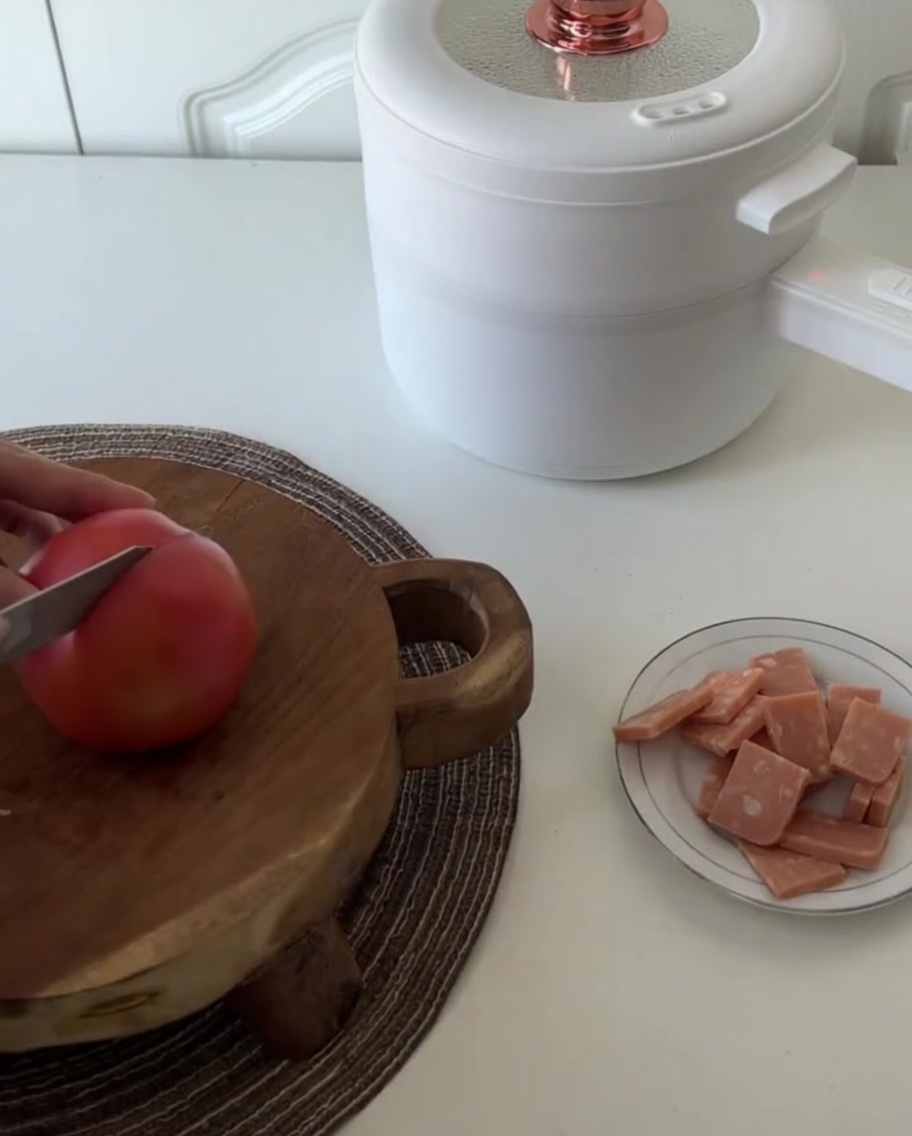 A fresh tomato being cut into four equal quarters on a cutting board.