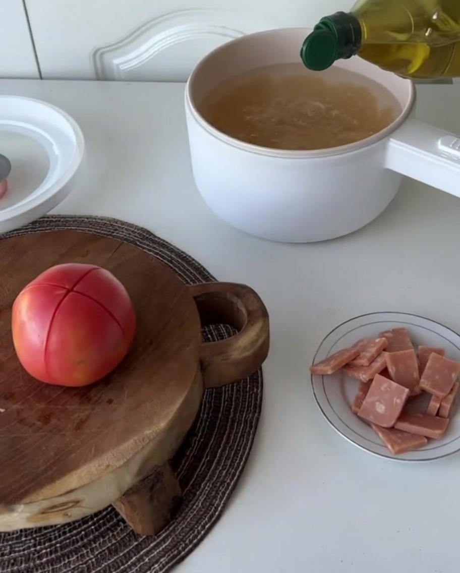 Dry fusilli pasta being added into a pot of water with a drizzle of oil.