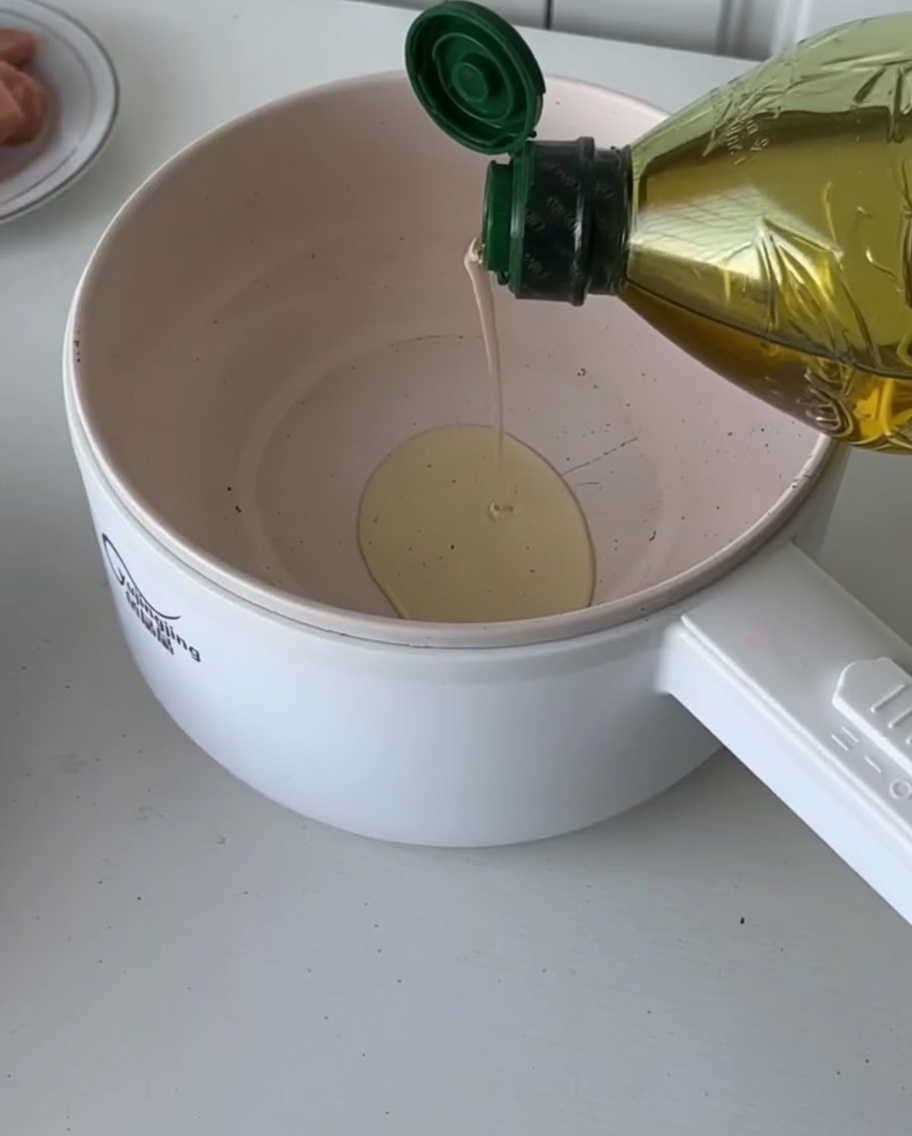 Oil being poured into a pan with freshly chopped onions ready to be sautéed.