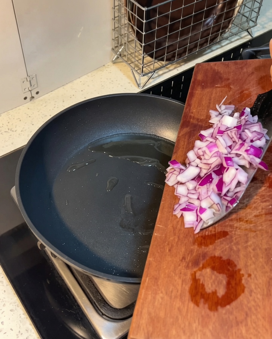 Diced onions being sautéed in a pan with melted butter.