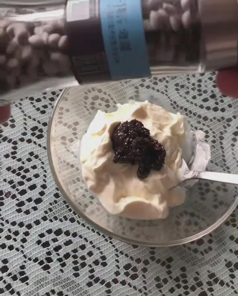 Black pepper being shaken from a grinder onto the sour cream and truffle sauce mixture.
