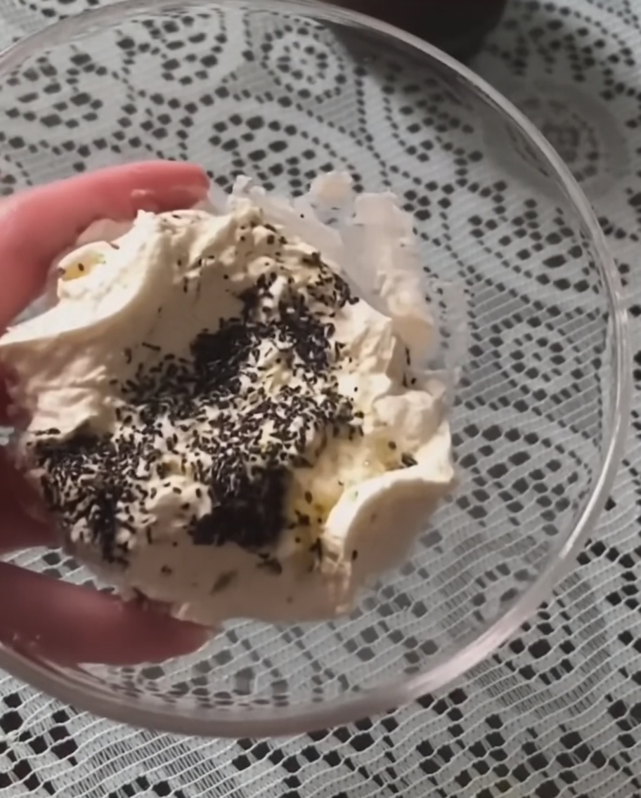 The sour cream and truffle sauce mixture being stirred in a glass bowl until smooth.