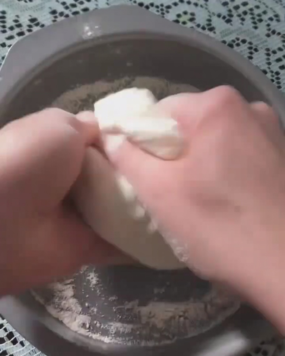 Hands pressing fermented pizza dough into a circular metal baking pan.