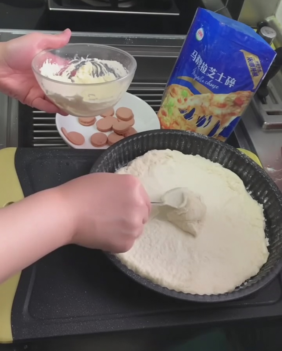 White truffle sauce being spread over the pizza dough using a spoon.