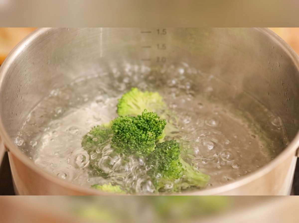 Broccoli and decorative carrot slices boiling in a pot of water.