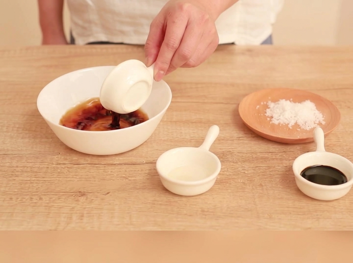 Sauce ingredients being stirred together in a small white bowl.