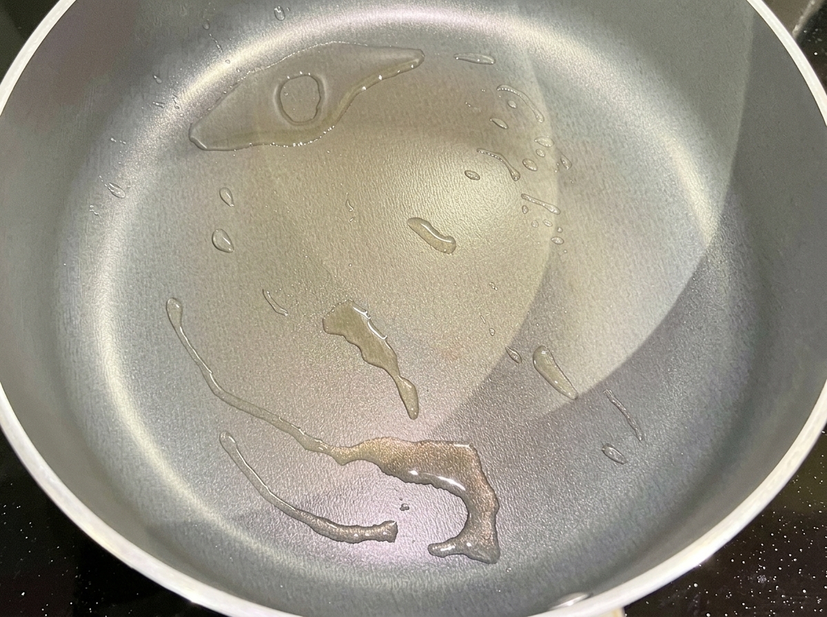 Chopped red onion sizzling in a pan with hot cooking oil.