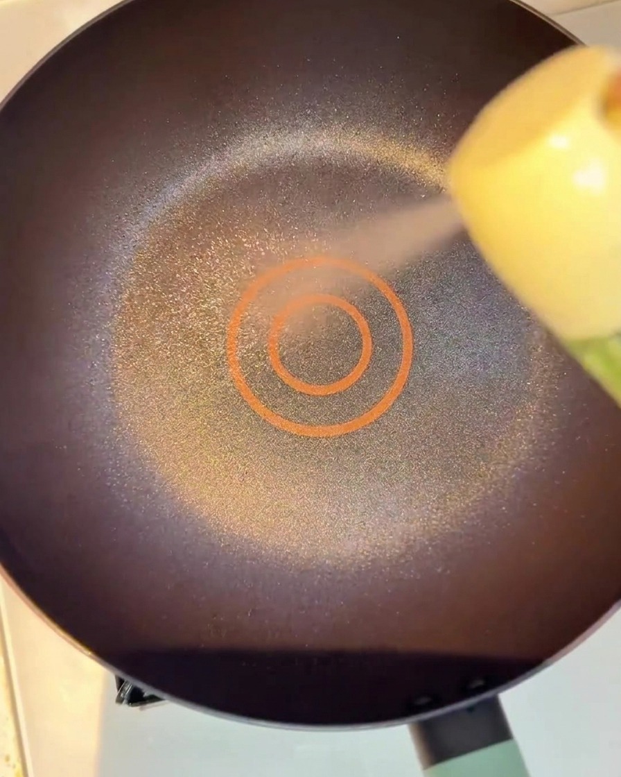 Marinated beef slices sizzling in a lightly oiled pan, beginning to brown.