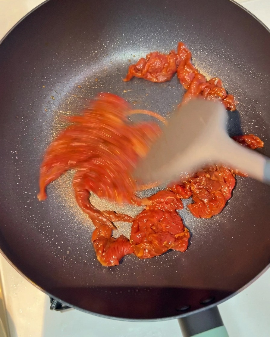 Beef pieces being stir-fried in a pan until browned and opaque.
