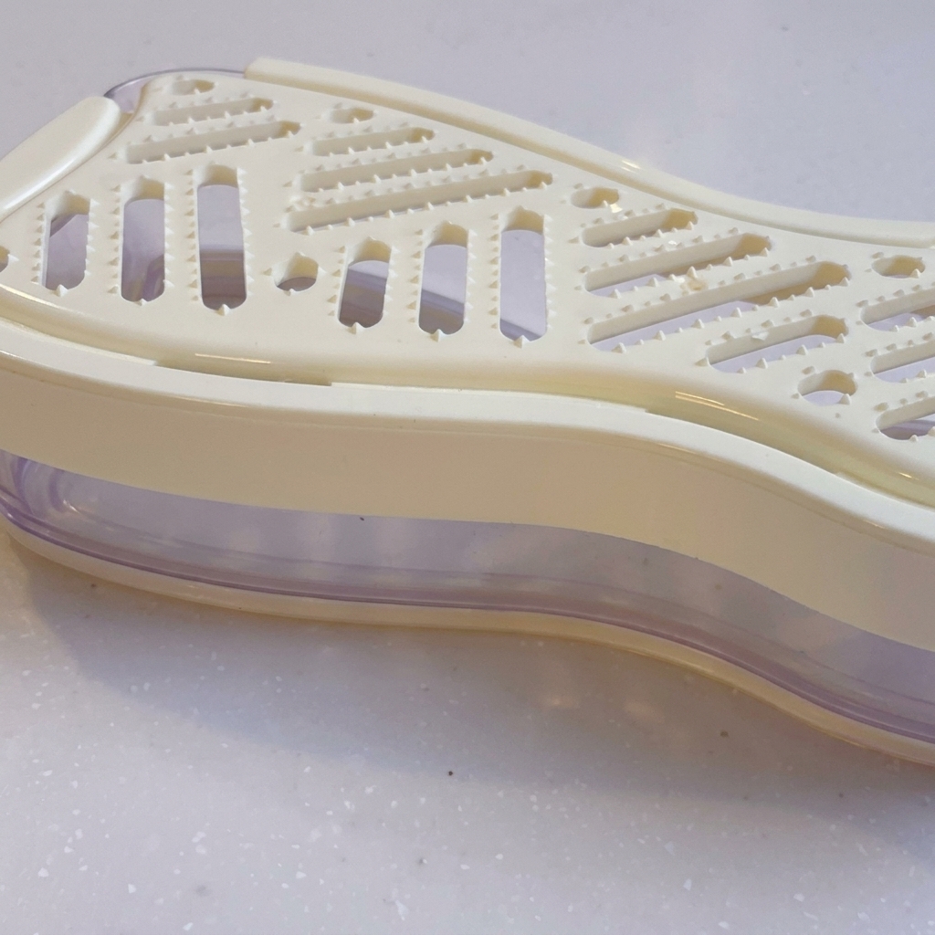 A close-up of a white manual grater with grated daikon radish inside.