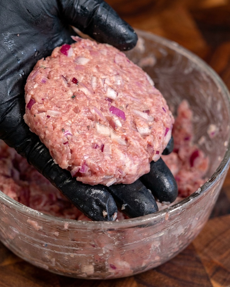 Several thick, round, seasoned beef patties shaped by hand.