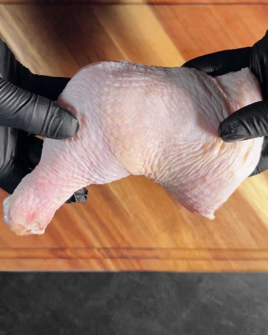 A deboned chicken leg in a metal tray, ready to be seasoned with aromatics.