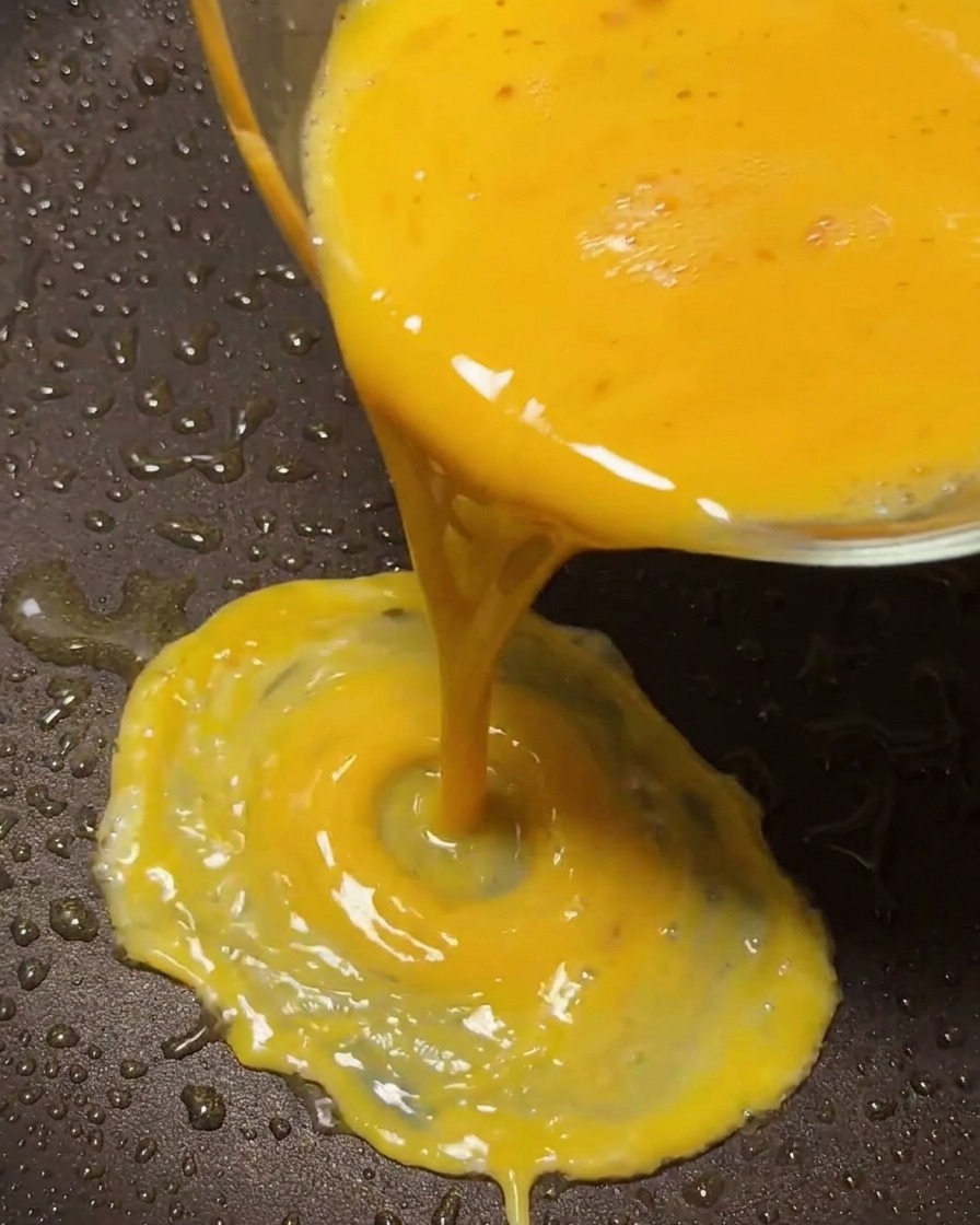 Soft egg curds forming in a hot pan.